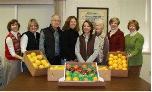 A group of people standing around some boxes of fruit.