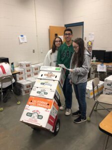 Three people stacking boxes in a room.